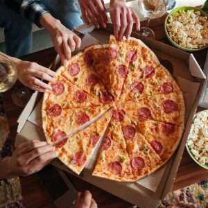 Top view of a group of friends eating big pizza